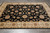 Black field hand-knotted wool rug displayed on grey tile floor showing all over palmette pattern