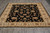 Ivory bordered black ground Oriental rug shown lengthwise with cream cotton fringe at near end