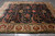 Hand-knotted wool rug on grey tile showing navy field and wide ivory floral palmette border