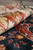 Rolled edge showing rust and gold border flowers against deep indigo blue wool pile surface
