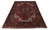 6'3" x 9'4" Persian Heriz rug photographed at an angle, showing dark floral border and ivory fringe