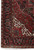 Corner view highlighting ivory fringe, black border with red rosettes and hand-knotted wool pile texture