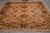 8 by 8.5 square Indian rug angled on grey tile, olive border and cream fringe visible
