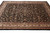9x12 Esfahan design rug photographed at an angle, dense vine and palmette pattern on black