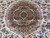 Detail of the round central medallion with salmon, black and teal floral tracery on ivory