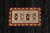 Close-up of small central cartouche with burgundy, gold and ivory arrow motifs on black wool