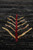 Detail of burgundy and gold cypress tree motif woven into the striated black wool field