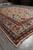 10 x 13 ivory Persian rug viewed lengthwise in showroom with fringe and wide border
