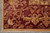 Corner close-up of burgundy border with gold palmettes, olive leaves and hand-knotted ivory fringe