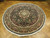 Angled floor view of the 8 foot round rug, ivory outer guard band and knotted fringe
