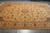 Angled floor view of the golden beige field, central rosette medallion and flowing vinework