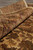 Rolled edge of the rug showing plush pile depth, brown border and honey beige field