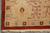Corner detail with ivory fringe, four-square rosettes and rust outer band on beige ground