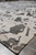 10x14 contemporary rug corner on gray tile showing finished edge and abstract pattern