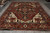 Rust red Oriental area rug displayed in showroom with ivory fringe and stepped corner spandrels