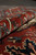 Rolled edge of Serapi wool rug revealing dense pile, firm selvage and rust red border