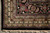 Corner of 8x10 Oriental rug with black main border, rosettes and clean ivory fringe