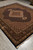 Living room sized 8x10 rug angled to show black outer border and cotton fringe