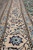 Ivory main border detail with blue rosettes, black outlines and flowing floral vine on this Nain rug