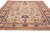 Angled view showing dusty rose border, navy guard stripes and the all-over floral field in wool