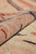Rolled edge close-up showing dense wool knots, dusty rose ground and red and blue outlines