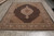 Angled showroom view of hand-knotted wool and silk Oriental rug with ivory center medallion