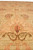 Detail of a coral palmette and brown vine scroll showing dense hand-knotted natural wool pile