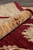 Rolled rug edge showing thick wool pile depth, burgundy ground and camel beige border