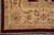 Corner detail of the wide beige border with palmettes, burgundy florets and ivory fringe