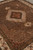 Diagonal view highlighting silk sheen across the brown herati field and ivory scalloped medallion frame