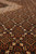 Pile-level close-up showing olive, ivory and rust herati knots across the chocolate brown field