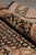 Rolled edge of black bordered rug showing thick wool pile and silk highlighted floral vinework