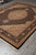Wide angled view of the black and beige Oriental rug placed on grey showroom tile