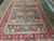 Large 10x12 Persian rug laid flat in the Freeport showroom, bright red and ivory tones