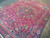 Angled view showing wool pile sheen, salmon guard stripe and navy main border of the rug