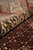 Rolled edge of the rug showing ivory palmette border against the deep red field