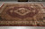 Ruby burgundy wool and silk area rug displayed flat on grey tile showroom floor