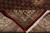 Folded corner revealing dense wool and silk pile, red selvage and cotton fringe