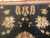 Detail of ivory and pink blossoms with small vase motif on black ground near border