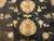 Close-up of two large cream palmettes surrounded by scattered floral sprays on black wool pile