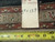 Back tag reading 9.9 x 13.9 beside a tape measure showing the woven foundation edge