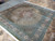 Angled view showing salmon main border, fish pattern field and fine hand-knotted wool pile
