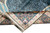 Folded corner of hand-knotted silk rug revealing fine weave, silk fringe and floral guard borders
