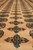 Low angle detail of diamond cross motifs running between gul rows across soft apricot pile