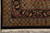 Corner detail of black floral border, rust vine scrolls and clean cotton fringe end