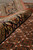 Rolled edge close-up showing dense wool and silk pile depth beside the rust herati field