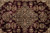 Detail of black floral medallion with pink, sage and gold blossoms on burgundy wool pile