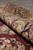 Rolled edge showing thick wool pile depth, black border flowers and burgundy field beneath