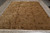 8'8" x 11'11" hand-knotted rug angled on grey floor with ivory fringe and olive brown field