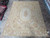 9' x 12' Aubusson rug displayed flat on stone floor showing full cream field and rose garlands